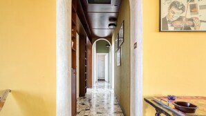 Un pasillo con piso de baldosas, una mesa de madera con un cuenco y cuadros en la pared.