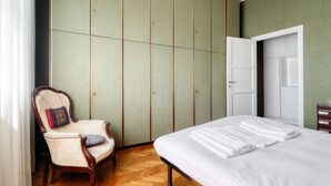 Una habitación con cama, una silla, un armario y una puerta.