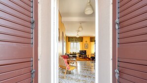 Un pasillo con piso de baldosas que conduce a una sala de estar con sofá, televisor y comedor.