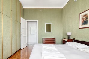 Een hotelkamer met een bed, nachtkastje, lamp, een inlijsting foto aan de muur en een kledingkast.
