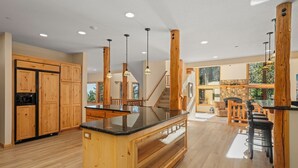 Una cocina amplia con gabinetes de madera, una isla central e iluminación colgante.