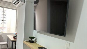Una sala de estar moderna con un televisor de pantalla plana grande montado en la pared, una consola de madera y una pequeña planta en maceta.