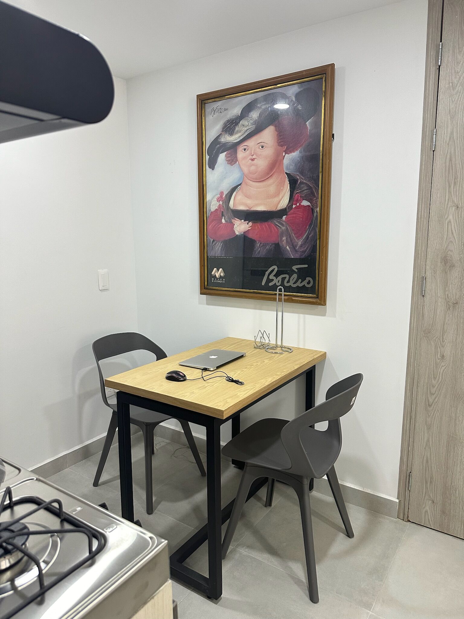 Un petit coin repas avec une table, des chaises et une œuvre d’art encadrée accrochée au mur.