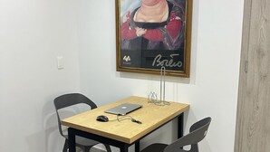 Un pequeño comedor con una mesa, sillas y una obra de arte enmarcada en la pared.