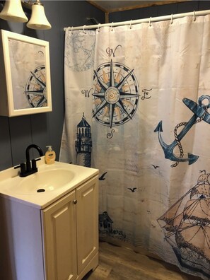 Bathroom features a nautical-themed shower curtain and a framed compass on the wall.