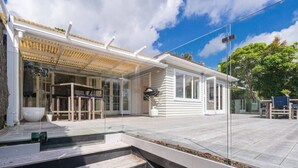Ein modernes Haus mit einer überdachten Terrasse, einem großen Fenster und einem gepflasterten Weg zum Eingang.