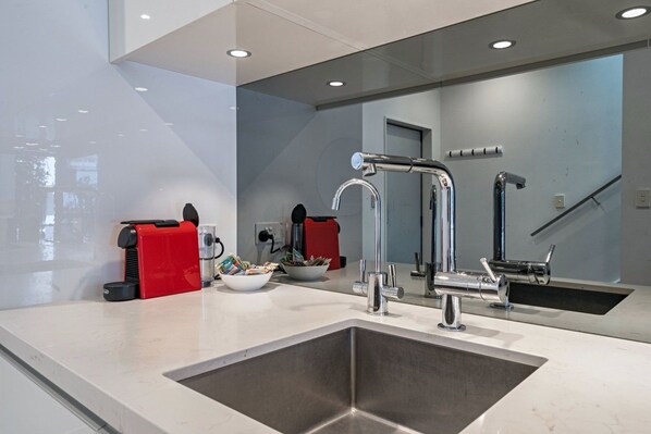 A modern bathroom with a large sink, a mirror, and a red towel warmer.