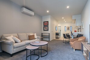 A modern living room with a sofa, coffee table, and dining area.