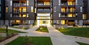A multi-story residential building with balconies, a central courtyard, and a well-maintained lawn. - Beautiful Garden Apartment| by Furnished Rentals (Auckland)
