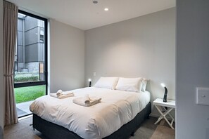 A modern bedroom with a large bed, bedside tables, and a window with curtains.