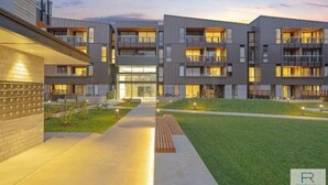 Een modern appartementencomplex met meerdere balkons, een centrale binnenplaats en een goed verlichte ingang.