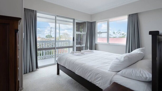 A bedroom with a large bed, a view of a balcony, and a ceiling light.