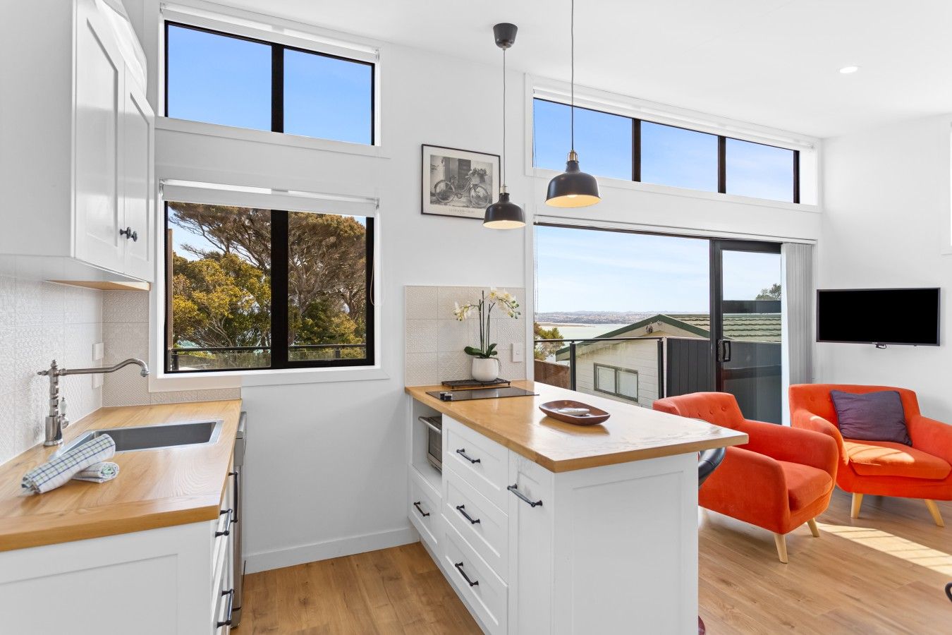 A modern kitchen with a wooden countertop, white cabinets, and a large window.