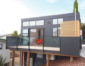 Une maison moderne à deux étages, dotée d’un balcon, de grandes fenêtres et d’un garage.