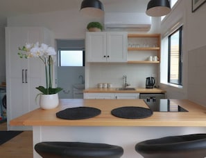 Une cuisine moderne avec des armoires blanches, un plan de travail en bois et un luminaire suspendu noir.