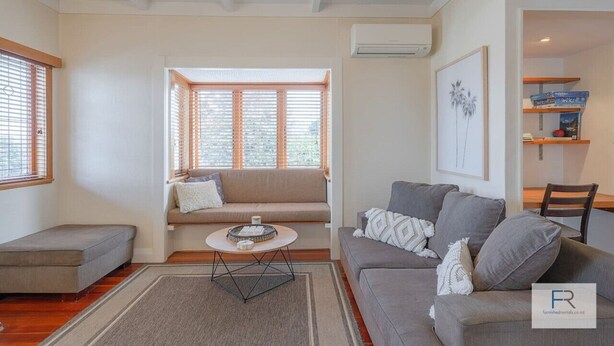 A living room with a sofa, a coffee table, and a window with blinds.