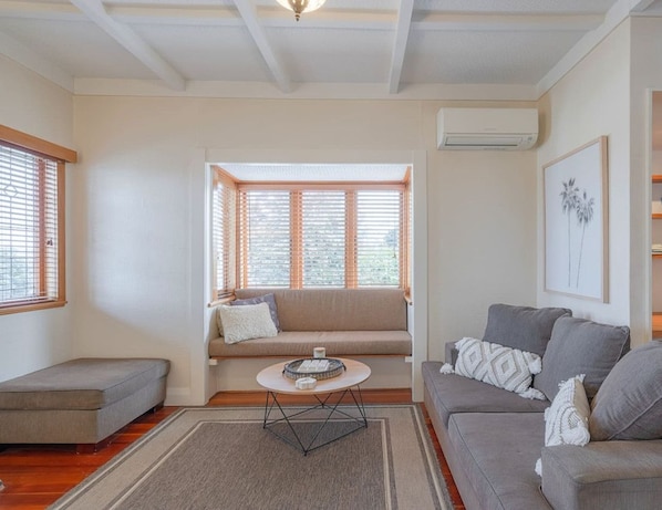 A living room with a sofa, a coffee table, and a window with blinds.