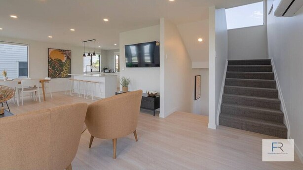 A modern living space with a kitchen, dining area, and staircase.