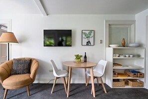 A modern living room with a sofa, two chairs, a round table, and a bookshelf. - Delightful Freemans Bay Home|by Furnished Rentals (Auckland)