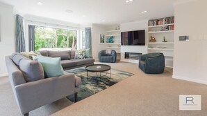 A modern living room with a grey sofa, a round coffee table, and a bookshelf. - Lux Living St Heliers|by Furnished Rentals (Auckland)