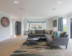 A modern living room with a sectional sofa, a coffee table, and a large window with curtains.