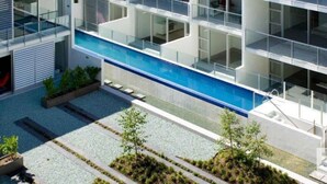 Ein modernes Gebäude mit einem zentralen Pool, mehreren Balkonen und einer Dachterrasse.
