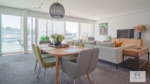 Ein modernes Wohnzimmer mit Essbereich, großen Fenstern und Blick auf die Stadt.