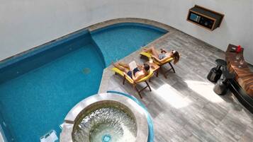 A swimming pool with two sun loungers and a hot tub.
