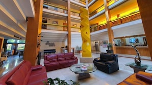 A spacious lobby with multiple floors, a central yellow spiral sculpture, and leather sofas. - Hotel Alcampo  (El Marques)
