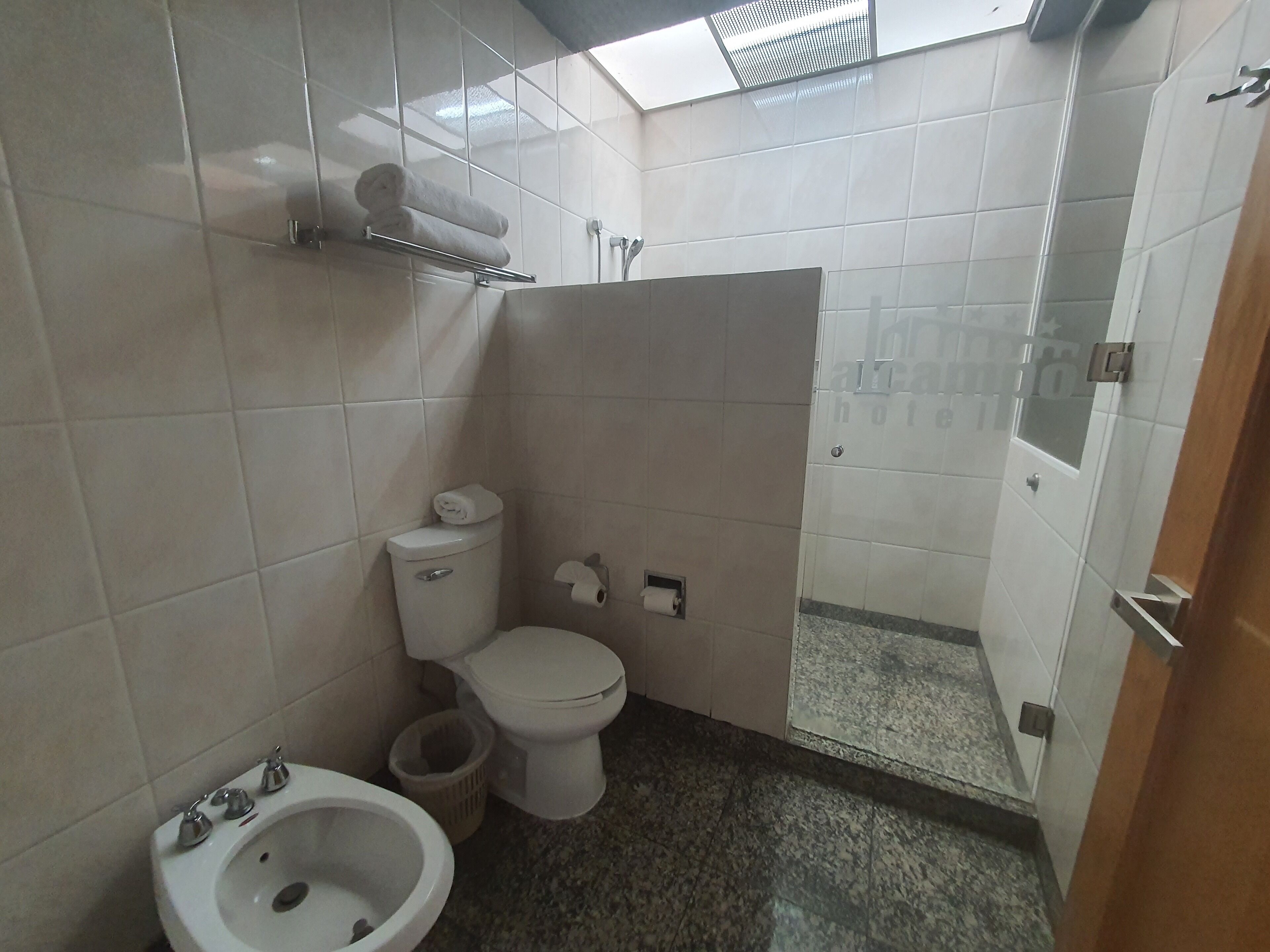 Baño con inodoro, bidé, lavabo y zona de ducha.