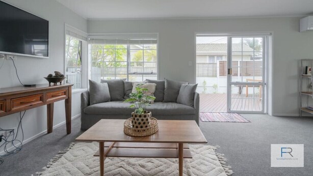 Un salon moderne avec un canapé gris, une table basse en bois et un téléviseur fixé au mur.