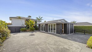 Une maison moderne à deux étages, dotée d’un patio couvert, d’un garage et d’une cour clôturée.