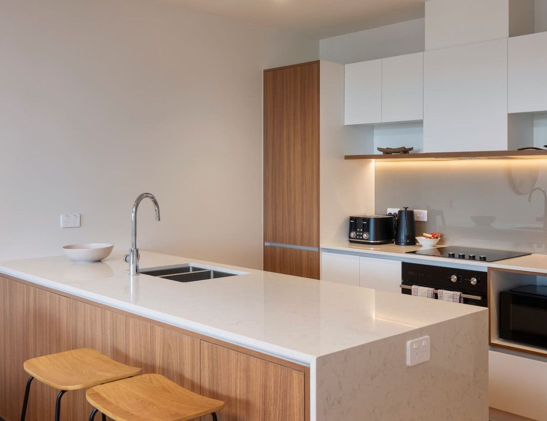 A modern kitchen with a central island, white cabinetry, and a microwave.