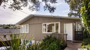 Einbungalow mit Haustür, kleiner Veranda und Holzterrasse.