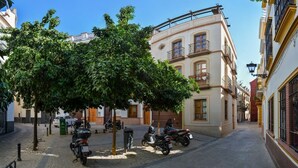 A narrow street with parked scooters and a tree-lined sidewalk. - DescubreHome Postigo, Inner Patio (Sevilla)