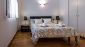 A neatly made bed with a patterned bedspread, two bedside lamps, and a bedside table with a green object. - DescubreHome Postigo, Inner Patio (Sevilla)