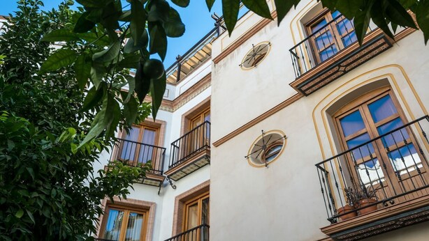 A multi-story building with balconies, large windows, and a clock on the facade. - DescubreHome Postigo, Inner Patio (Sevilla)