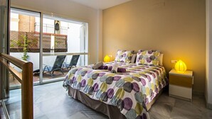 Et soveværelse med en stor seng, to sengeborde, et vindue med udsigt og en balkon med stole.