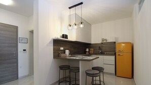 A compact kitchen with a built-in island, bar stools, a vintage-style refrigerator, and modern pendant lighting. - Apartment 2355/115856 (Istria - Peroj), 1250m from the beach (Peroj)