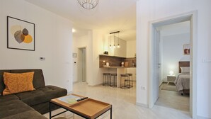 A modern living room with a sofa, a coffee table, and a kitchen area with bar stools. - Apartment 2355/115856 (Istria - Peroj), 1250m from the beach (Peroj)