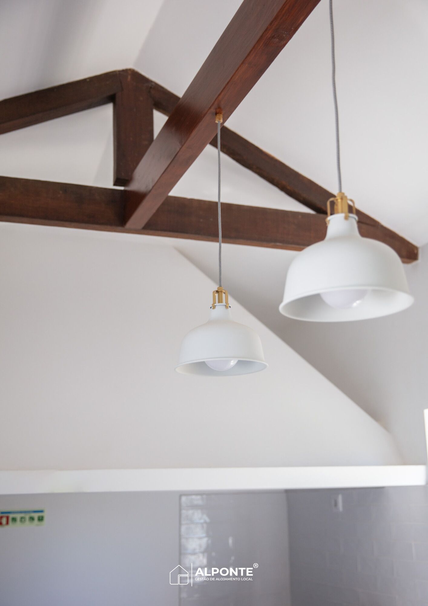 A ceiling with exposed wooden beams and two white pendant lights.