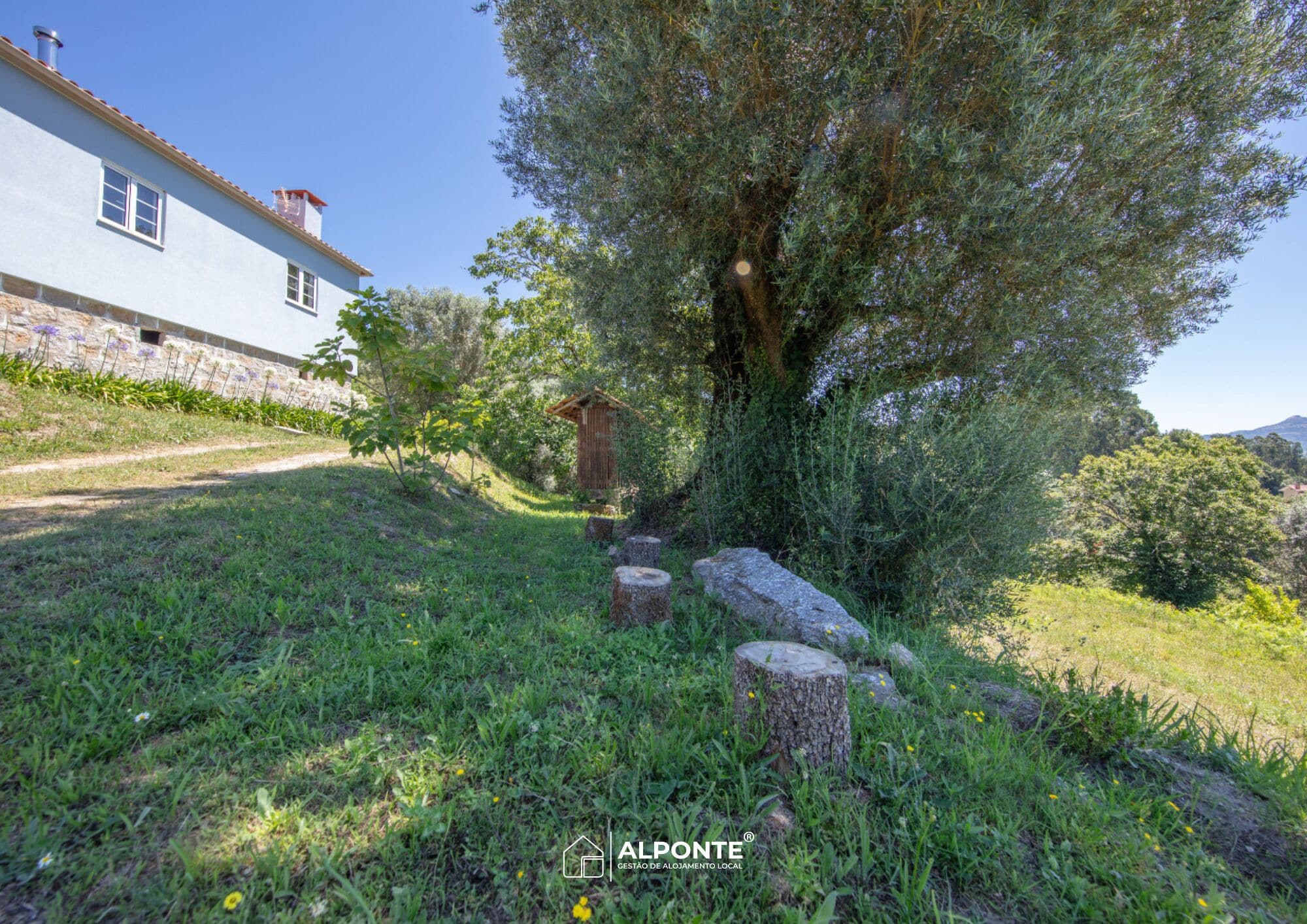 Una casa de piedra rústica con un sendero de jardín que conduce a una estructura de madera.
