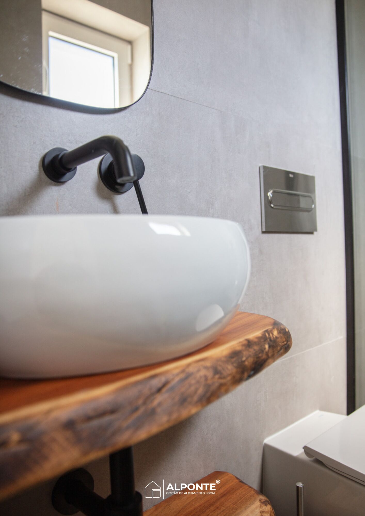 Un baño moderno con un lavabo blanco, encimera de madera y un espejo.