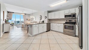 A modern kitchen with white cabinets, stainless steel appliances, and a large island.