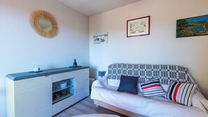 Una sala de estar moderna con un sofá, un armario blanco y un espejo redondo en la pared.
