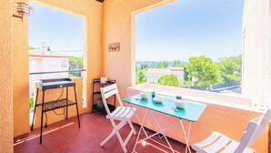 Un balcón con una mesa, sillas y un estante pequeño.