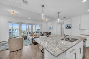 A spacious kitchen with a large island, white cabinetry, and a dining area with a view.