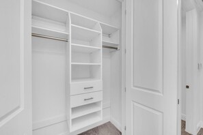 Ein begehbarer Kleiderschrank mit offenen Türen, der Regale und Schubladen zeigt.