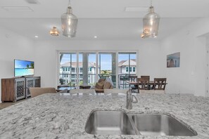 A spacious kitchen with a large island, stainless steel sink, and pendant lighting.
