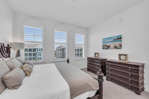 A bedroom with a large bed, two dressers, and a painting on the wall.